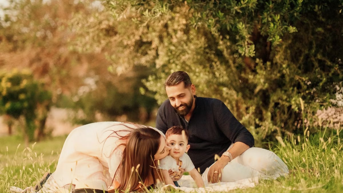 A joyful family with parents and a baby enjoying a sunny day outdoors on a picnic.